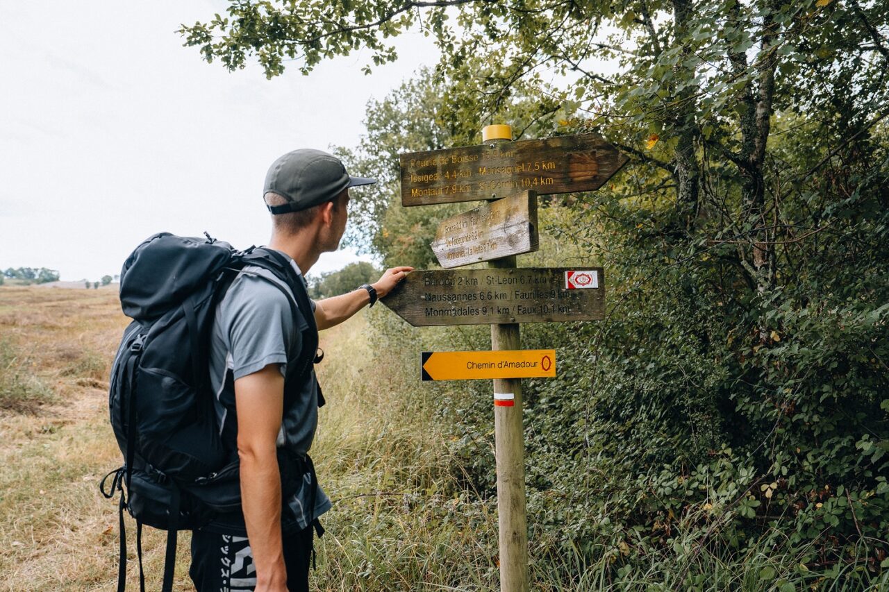 Randonneur consultant un panneau directionnel sur le Chemin d’Amadour